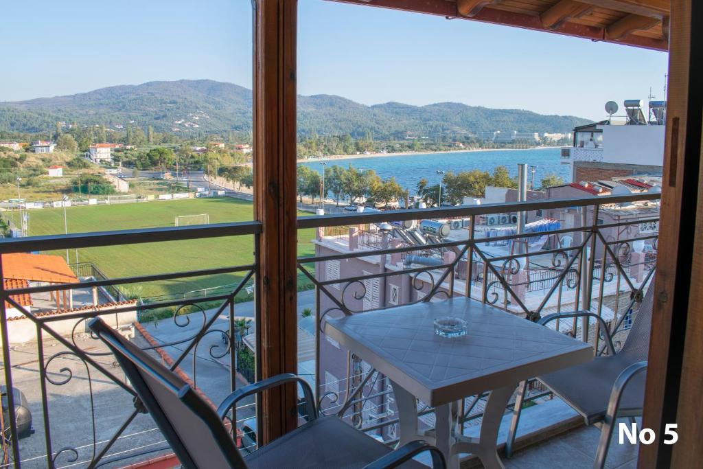 balcone con tavolo, sedie e vista sull'acqua di Sofias Studios East Home a Néos Marmarás