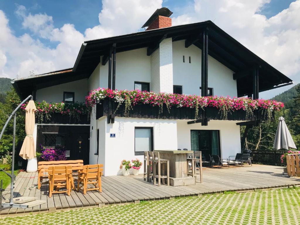 a white house with a deck with tables and chairs at Landhaus Zirben in Bad Kleinkirchheim