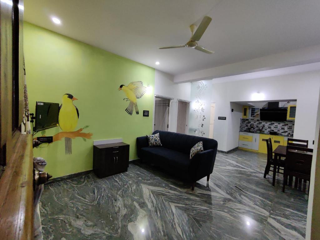 una sala de estar con sofá y aves pintadas en la pared en Vogel's Nest, en Mysore