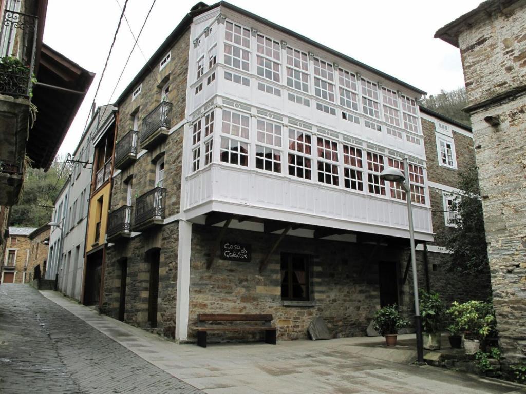 un grand bâtiment blanc sur le côté d'une rue dans l'établissement Habitación Cuadruple con derecho a Barbacoa y patio, à Navia de Suarna