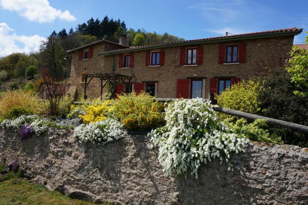a stone wall with flowers in front of a house at Auberge du Thiollet in Montromant