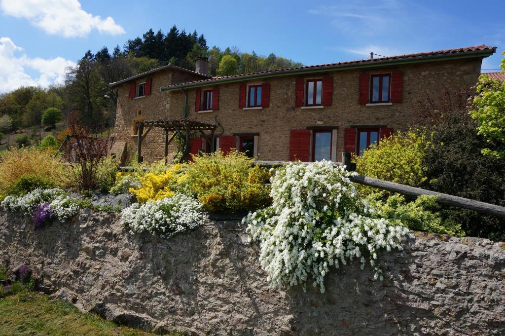 un mur en pierre avec des fleurs devant une maison dans l'établissement Auberge du Thiollet, à Montromant