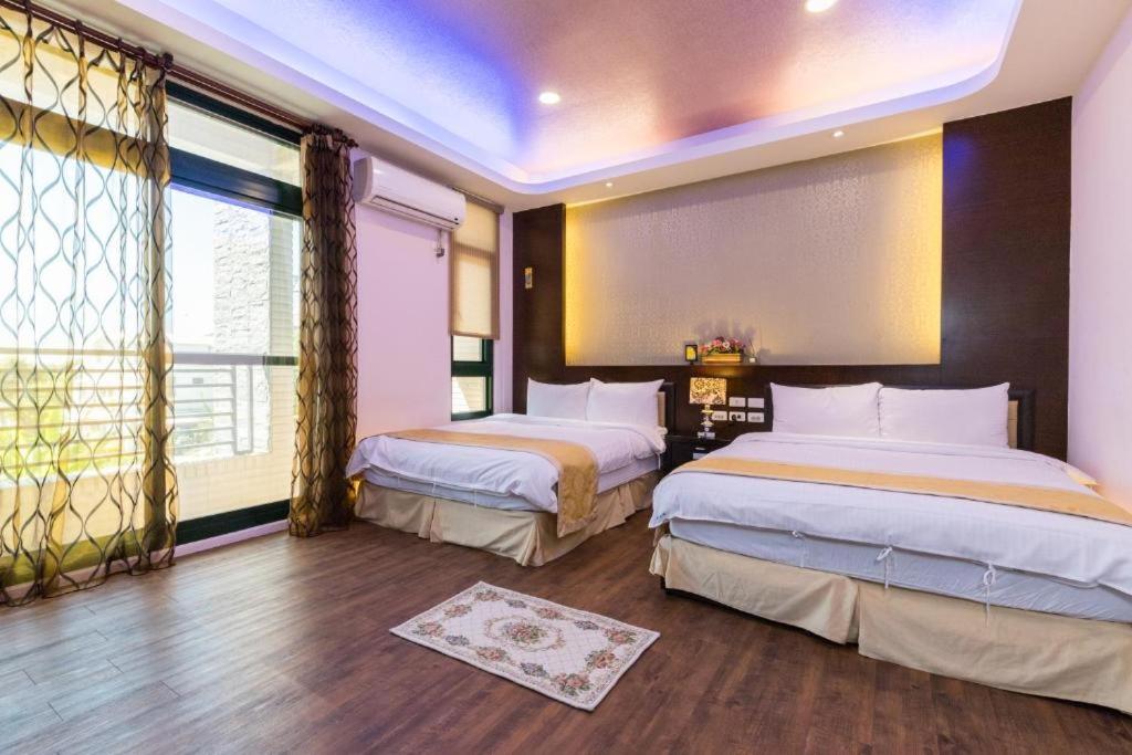 a bedroom with two beds and a large window at Qing Jing Ze Bed &amp; Breakfast in Hualien City