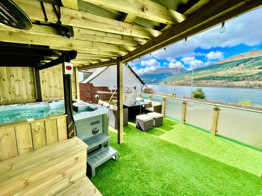a hot tub on the deck of a boat on the water at Amazing Alps and Loch views - HOT TUB and pet friendly in Arrochar