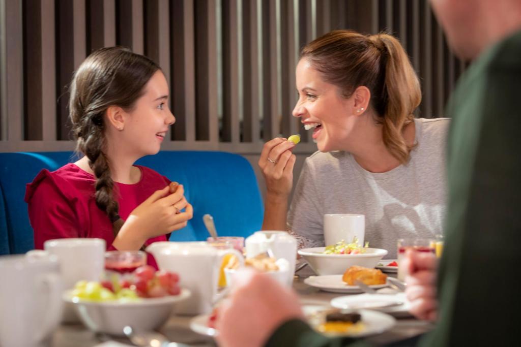 a woman and a girl sitting at a table eating food at Clayton Hotel & Leisure Club Sligo in Sligo