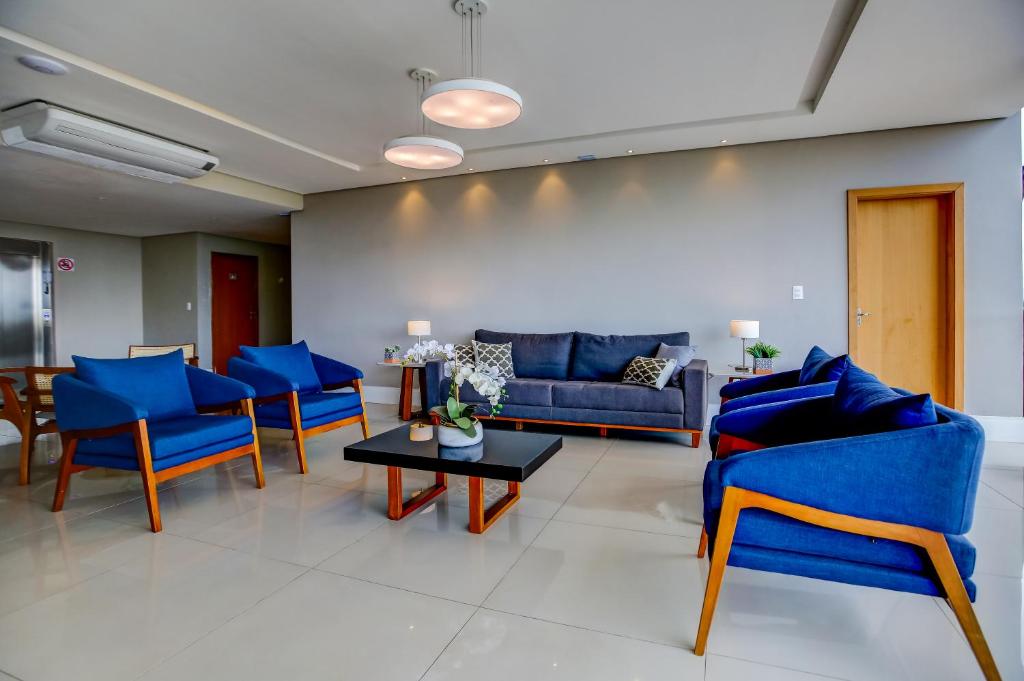 uma sala de estar com cadeiras azuis e uma mesa em Go Inn Betim - MG em Betim