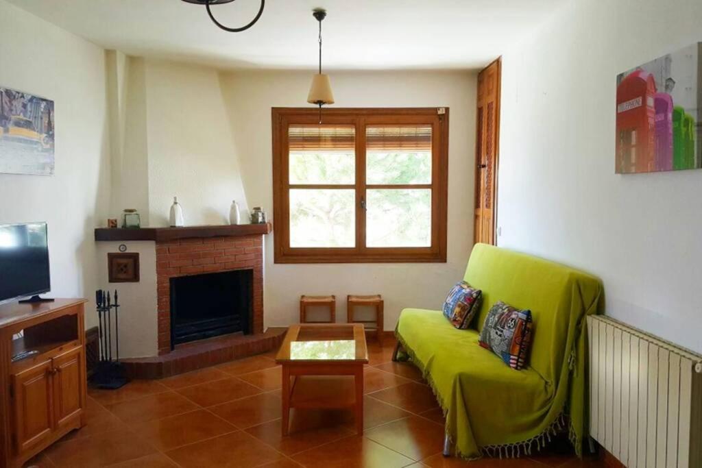 a living room with a green couch and a fireplace at Apartamento Rústico VILLA MOCA Bubión in Bubión