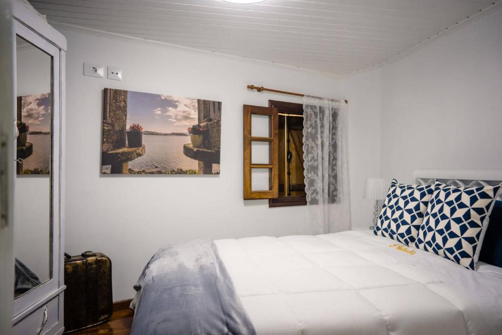 a white bedroom with a bed and a window at Casa A Boleriña in Combarro