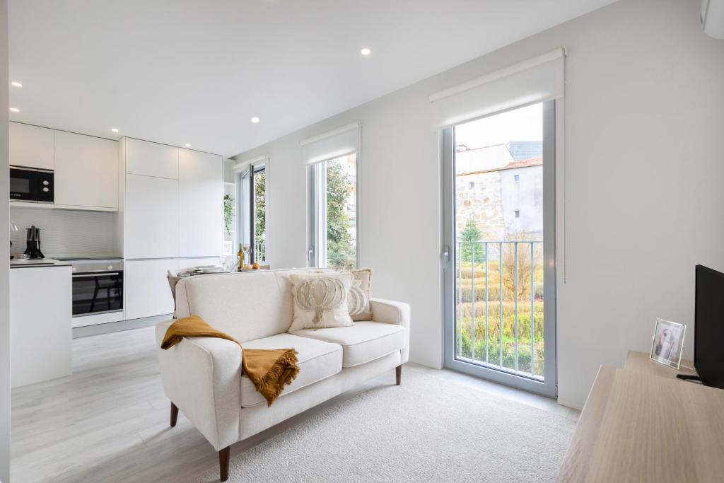 a white living room with a white couch and a window at Modern Studio @ Palácio de Cristal in Porto