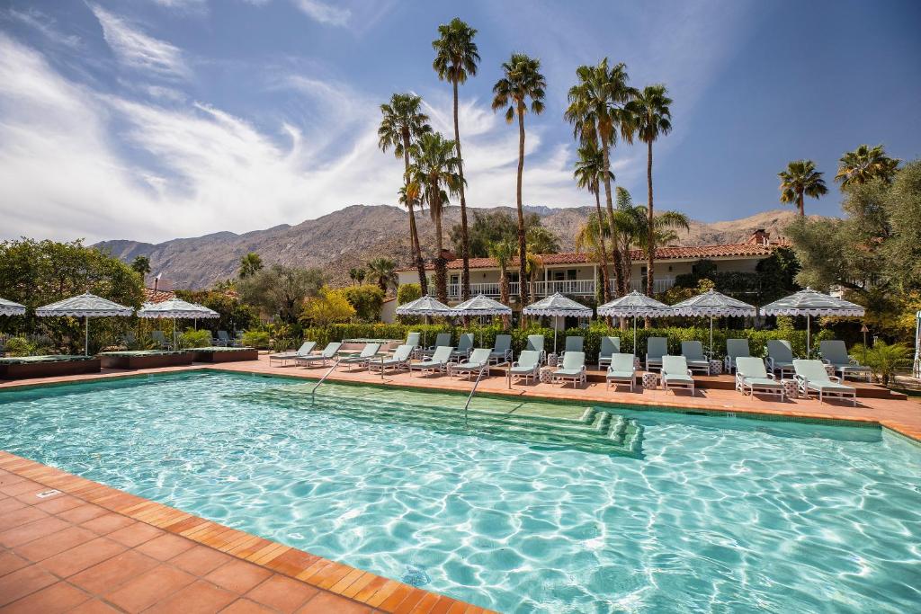 einen Pool mit Stühlen und Palmen in der Unterkunft The Colony Palms Hotel and Bungalows - Adults Only in Palm Springs