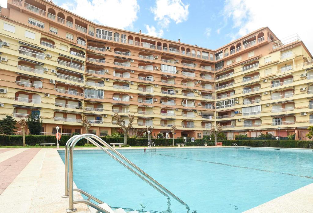 a swimming pool in front of a large building at APCOSTAS Los Iris - familiar in Playa de Gandia
