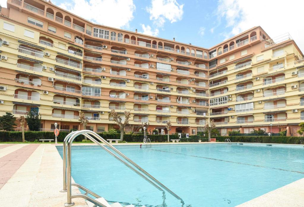 uma piscina em frente a um grande edifício em APCOSTAS Los Iris - familiar em Playa de Gandia