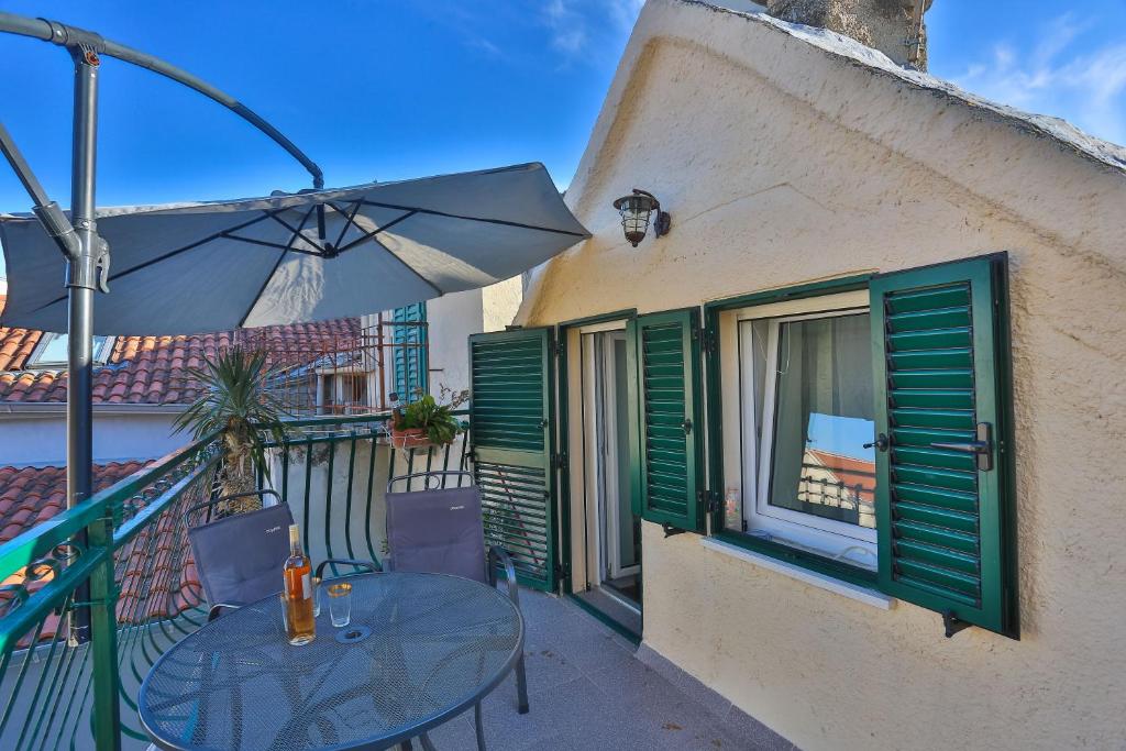 eine Terrasse mit einem Tisch und einem Sonnenschirm auf dem Balkon in der Unterkunft Apartment Matejuška in Split