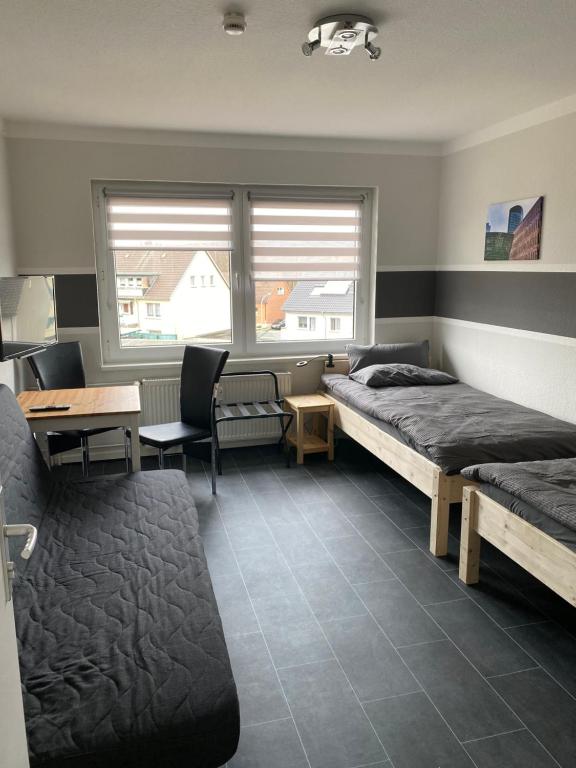 a bedroom with two beds and a desk and a table at Ferienwohnung Hagen in Hagen