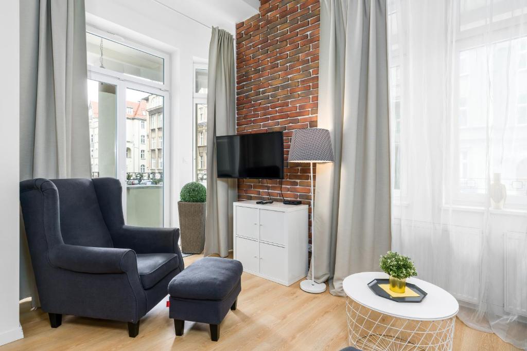 a living room with a chair and a tv at Apartment Poznan MTP Chełmońskiego by Renters in Poznań