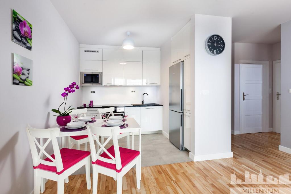 a white kitchen with a table and chairs in a room at Millennium La Tour in Warsaw