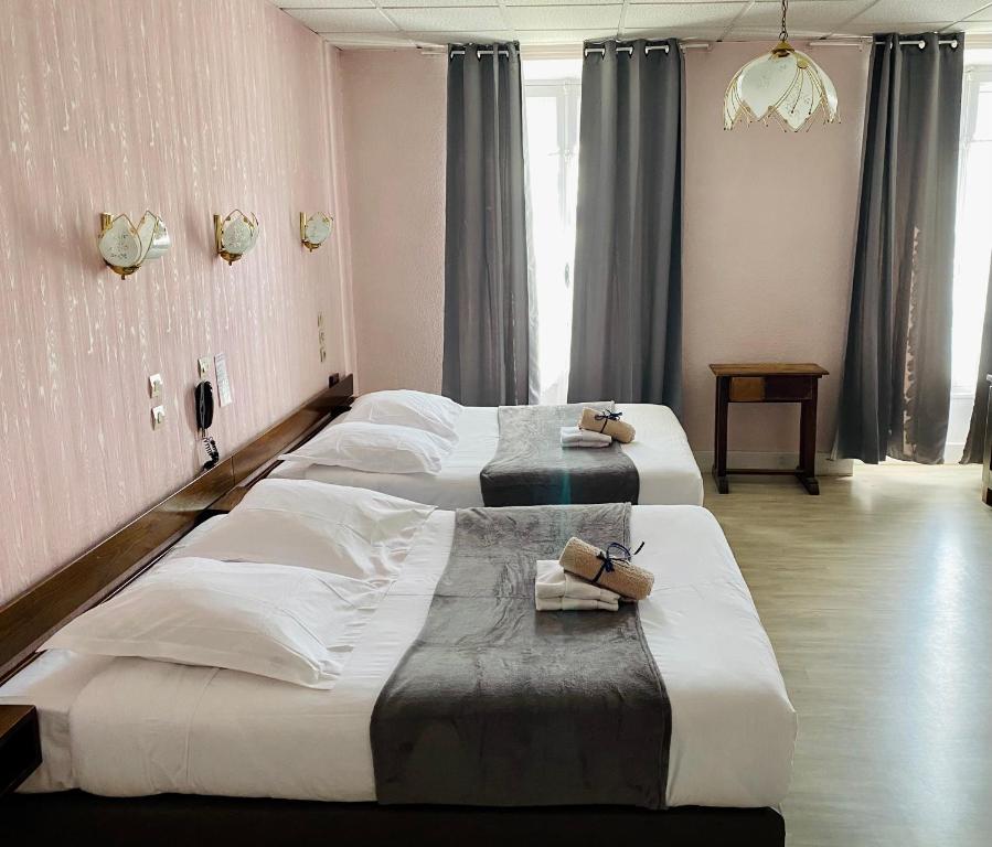 Dos camas en una habitación de hotel con toallas. en Hôtel des Alpes en Aix-les-Bains