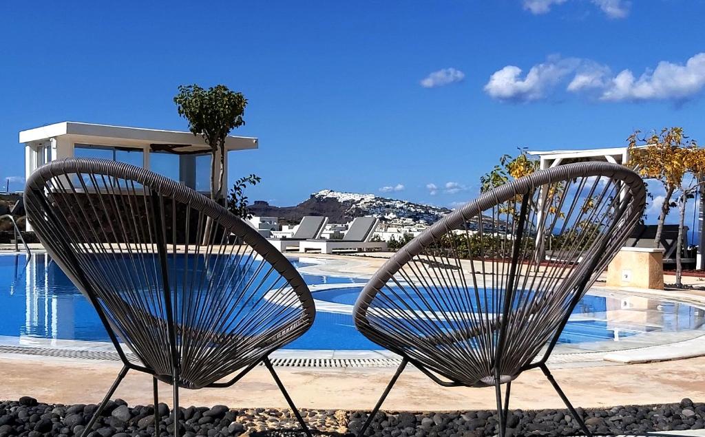 dos sillas de metal sentadas junto a una piscina en Santorini Mesotopos, en Fira