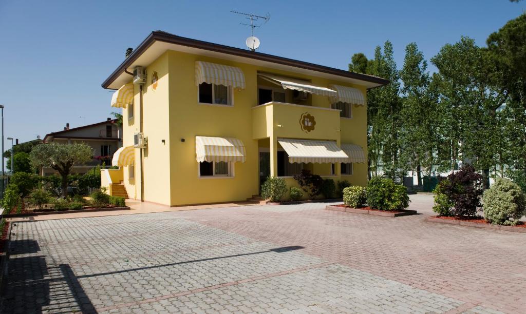 um edifício amarelo numa estrada de tijolos em Appartamenti Mimi em Lido di Jesolo