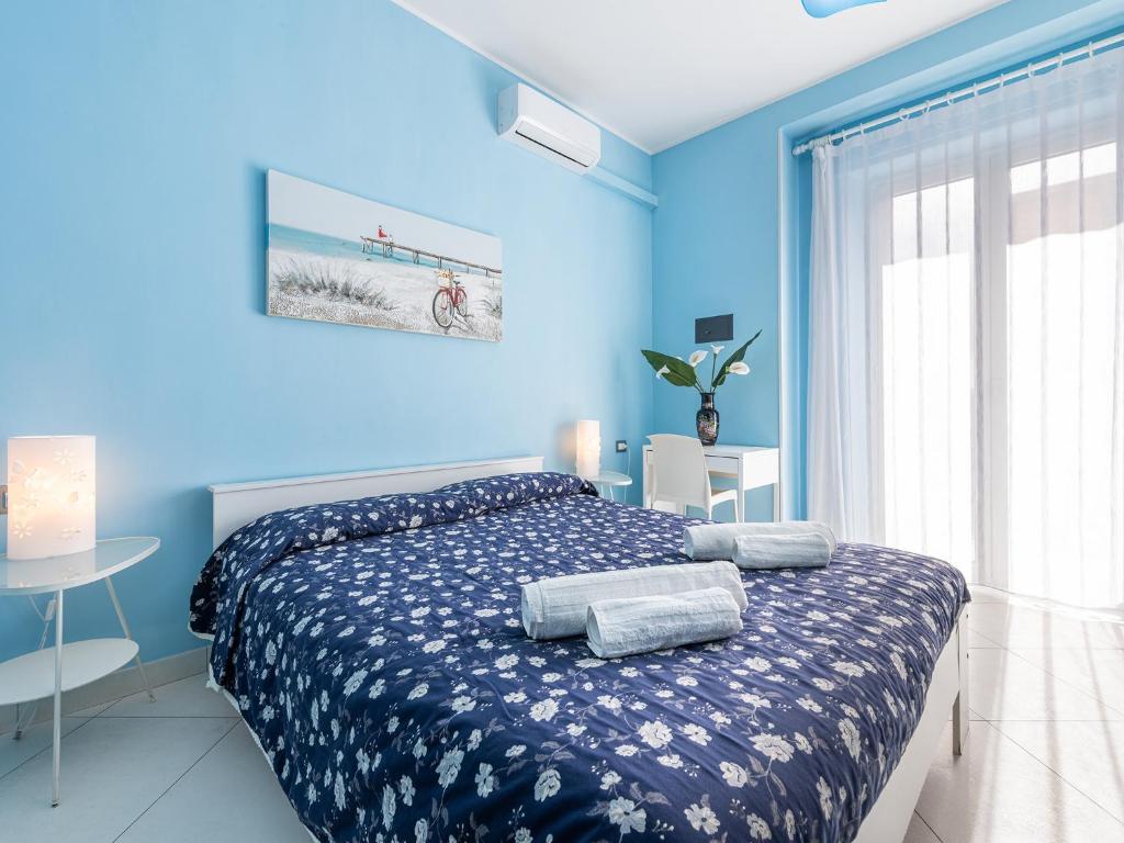 a bedroom with blue walls and a bed with towels on it at Thanit Rooms in Cagliari