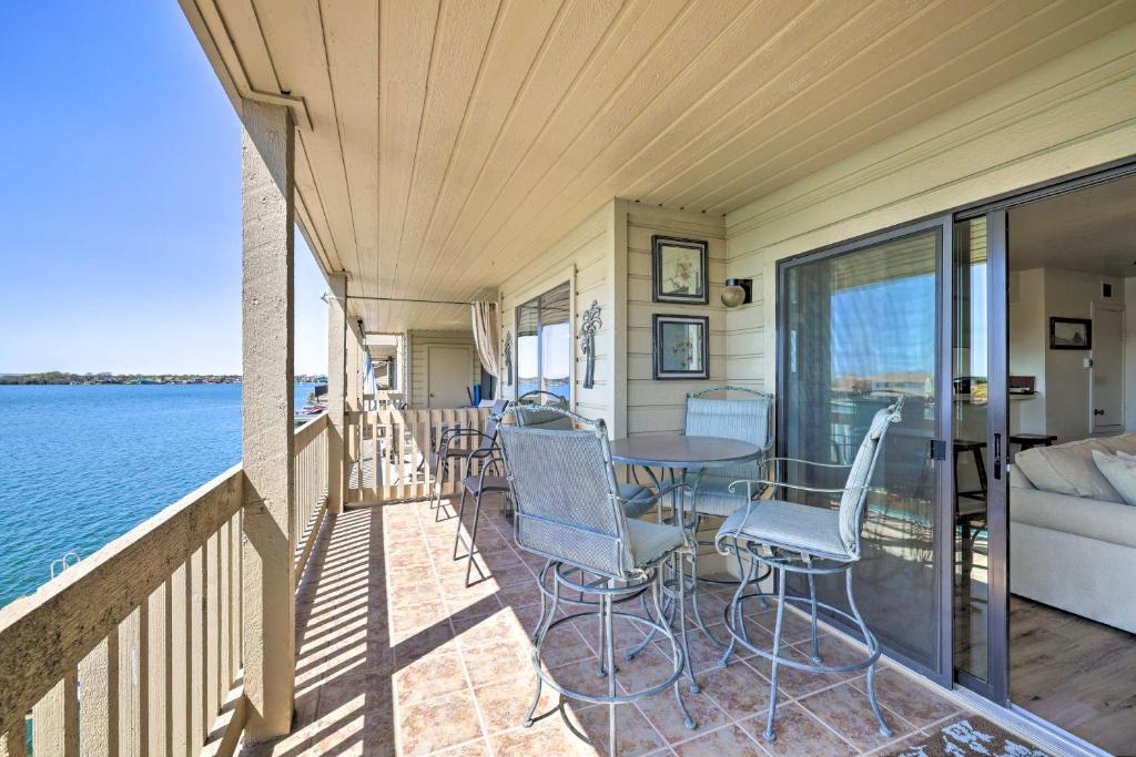 a porch with chairs and a table on the water at Waterfront Condo with Balcony and Dock Access in Horseshoe Bay