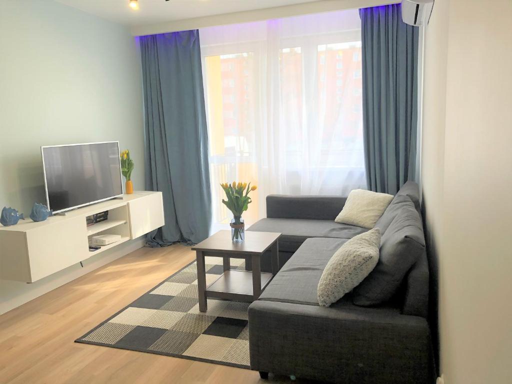 a living room with a couch and a tv at Apartament Blisko Morza i Parku Gdańsk Brzeźno in Gdańsk