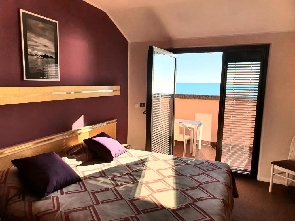 a bedroom with a bed with a view of the ocean at Hotel Antares in Grado