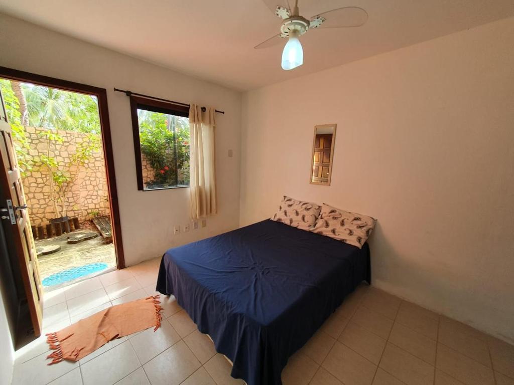 een slaapkamer met een bed en een groot raam bij Itacimirim village pé na areia in Itacimirim