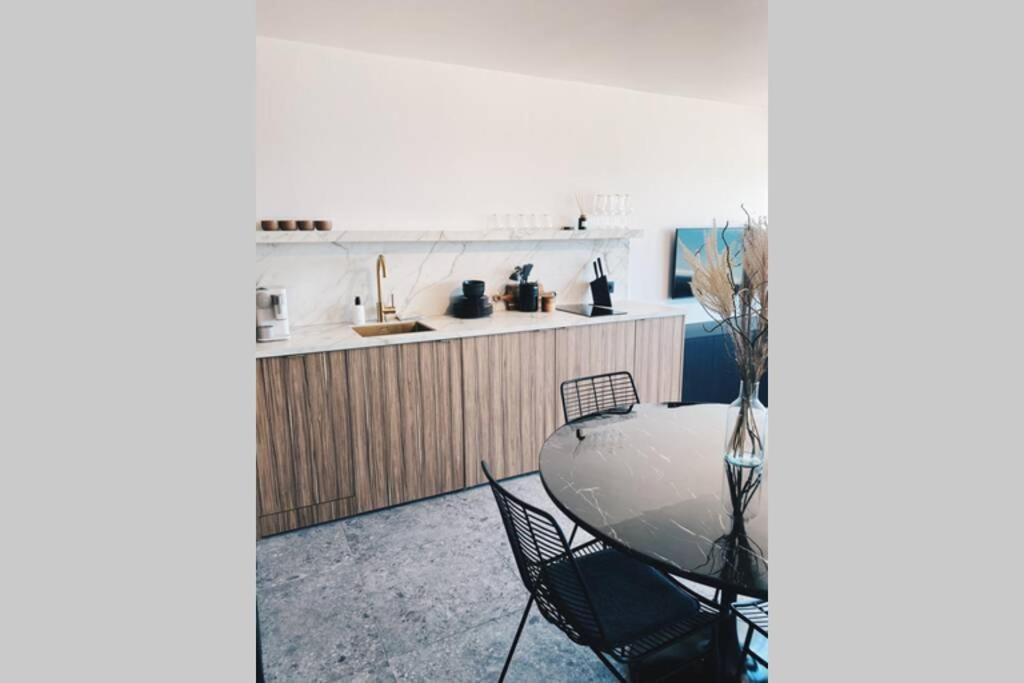 a kitchen with a table and chairs in a room at Wonderful architect designed flat with sea view in Ostend