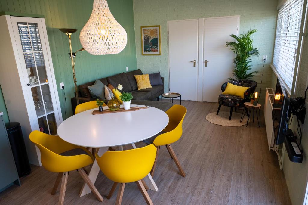 a living room with a table and yellow chairs at iwalani Beach Bungalow - large Private Garden - close to City Center & Beach in De Koog