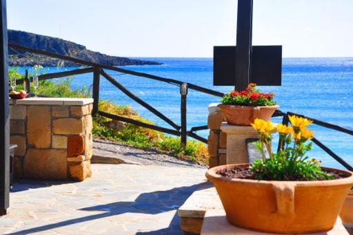 a patio with flowers and a view of the ocean at Coral Front Beach in Kato Zakros