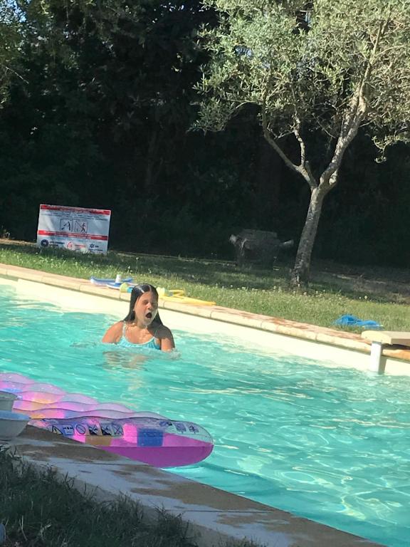 une femme dans une piscine avec une planche de surf dans l'établissement gite au paradis, parc animalier, à Olmeta-di-Tuda