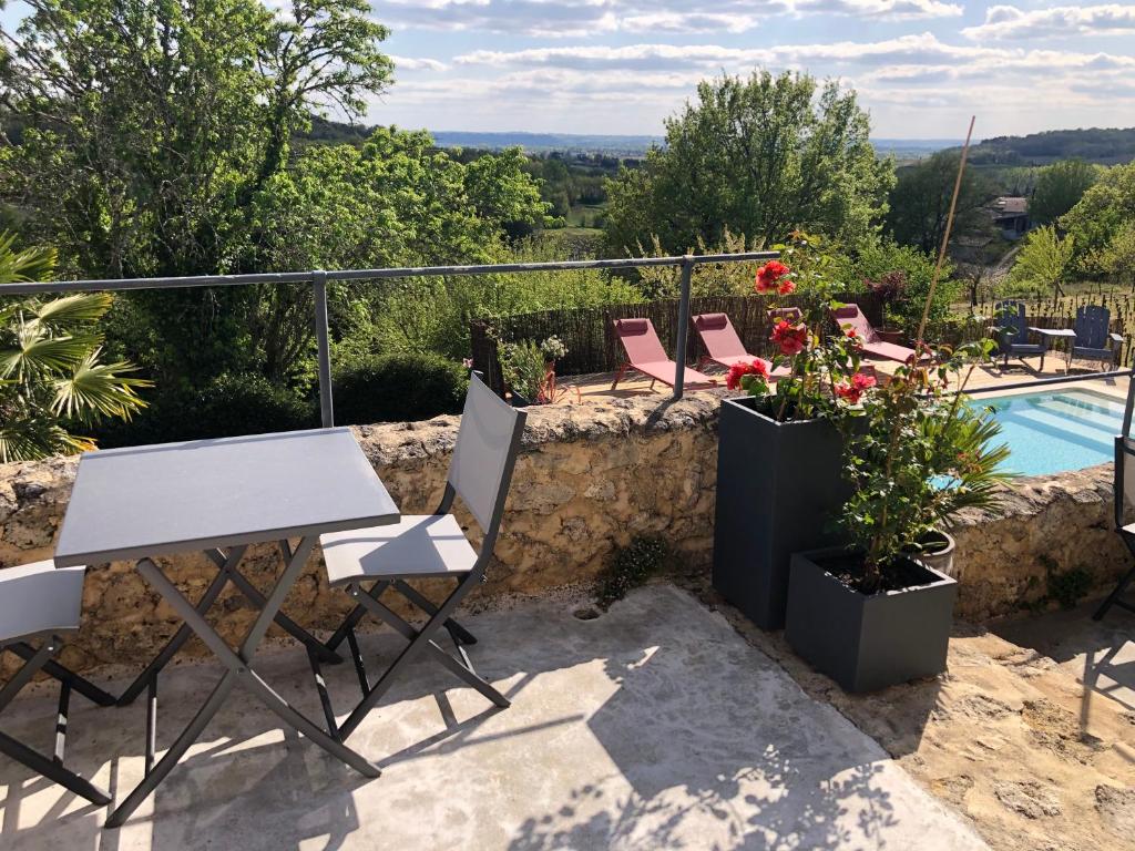 une terrasse avec une table, des chaises et une piscine dans l'établissement Château Haut-Clarise, à Belvès-de-Castillon