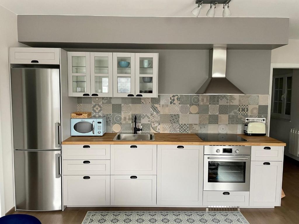 una cucina con armadi bianchi e frigorifero in acciaio inossidabile di Alojamientos con encanto Ruliña a Portomarin