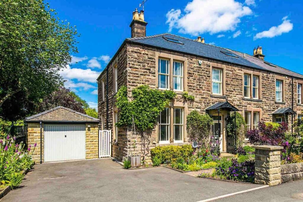 a brick house with a garage in front of it at Lynwood - Victorian Home in the Peak District in Bakewell