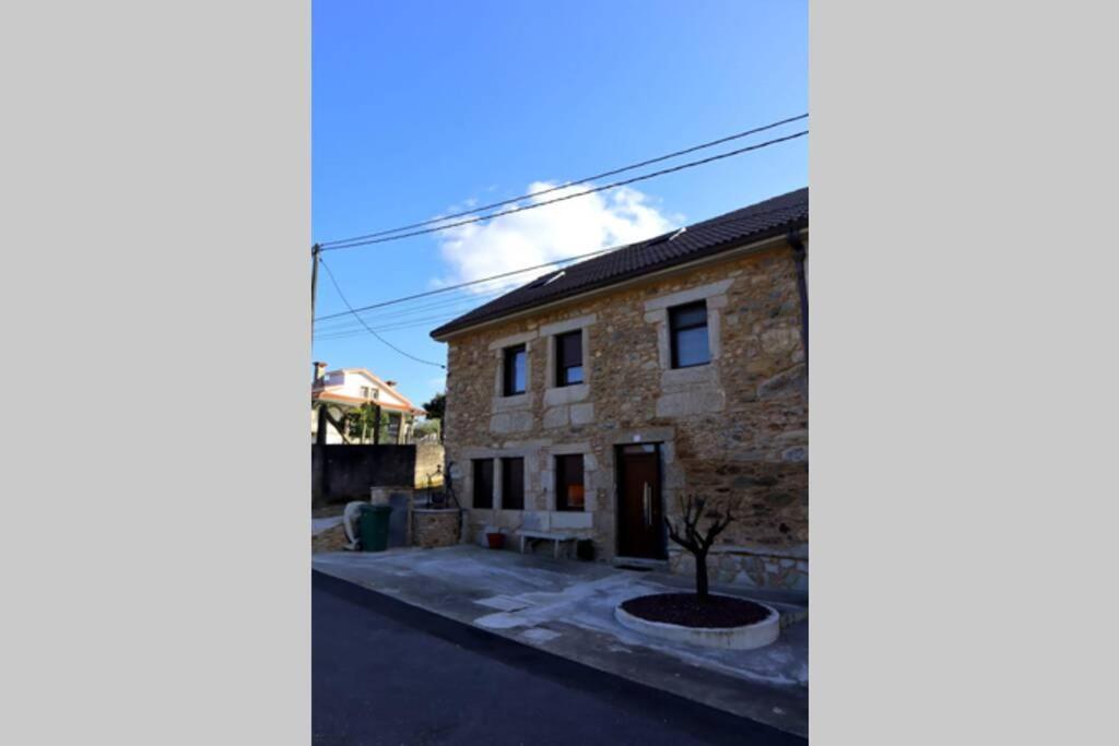 une maison en pierre avec un arbre en face de celle-ci dans l'établissement Apartamento CATA Santiago de Compostela, à Saint-Jacques-de-Compostelle