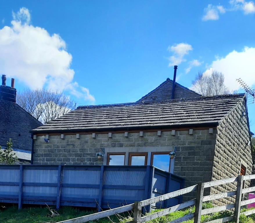 ein Backsteinhaus mit einem Zaun davor in der Unterkunft Bank Bottom Cottage in Marsden