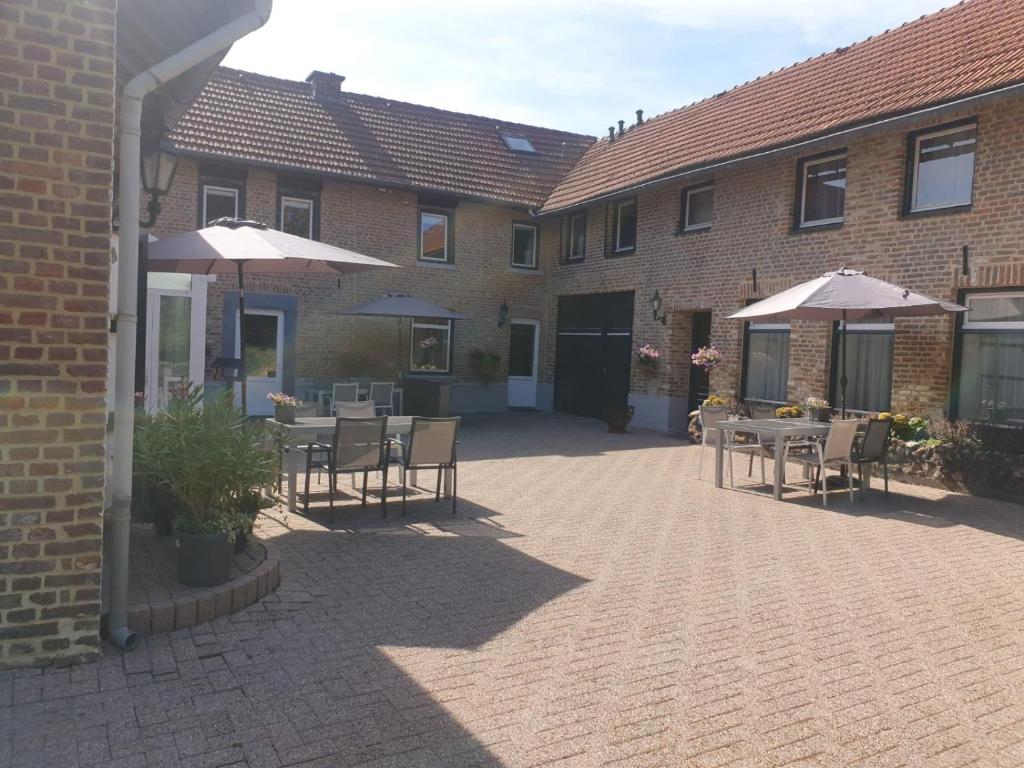 a patio with tables and umbrellas in front of a building at Lodewijkhoeve in Banholt