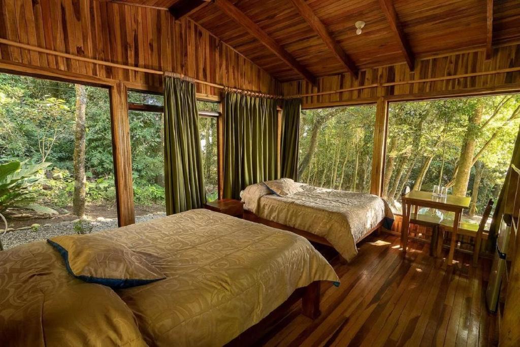 een slaapkamer met 2 bedden in een kamer met ramen bij Hotel Flor de Bromelia in Monteverde Costa Rica