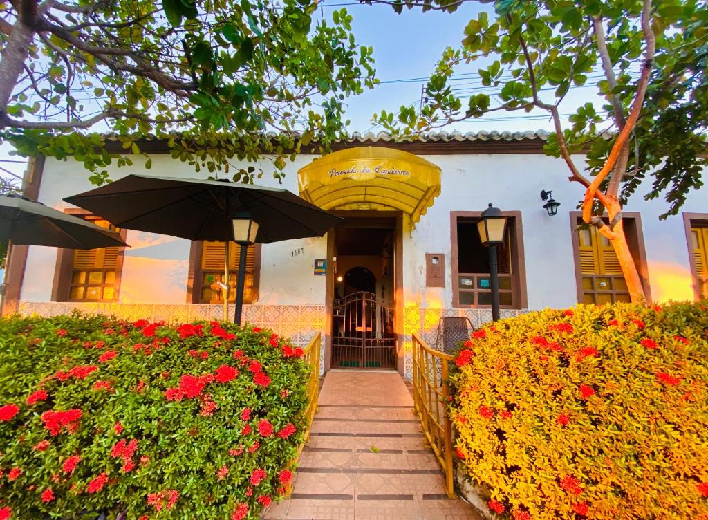 a building with an umbrella and flowers in front of it at Pousada dos Candeeiros in Carolina