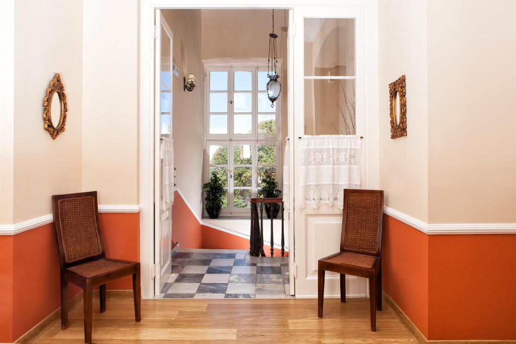 2 Stühle im Flur mit orangefarbenen und weißen Wänden in der Unterkunft Egli Hotel in Ándros