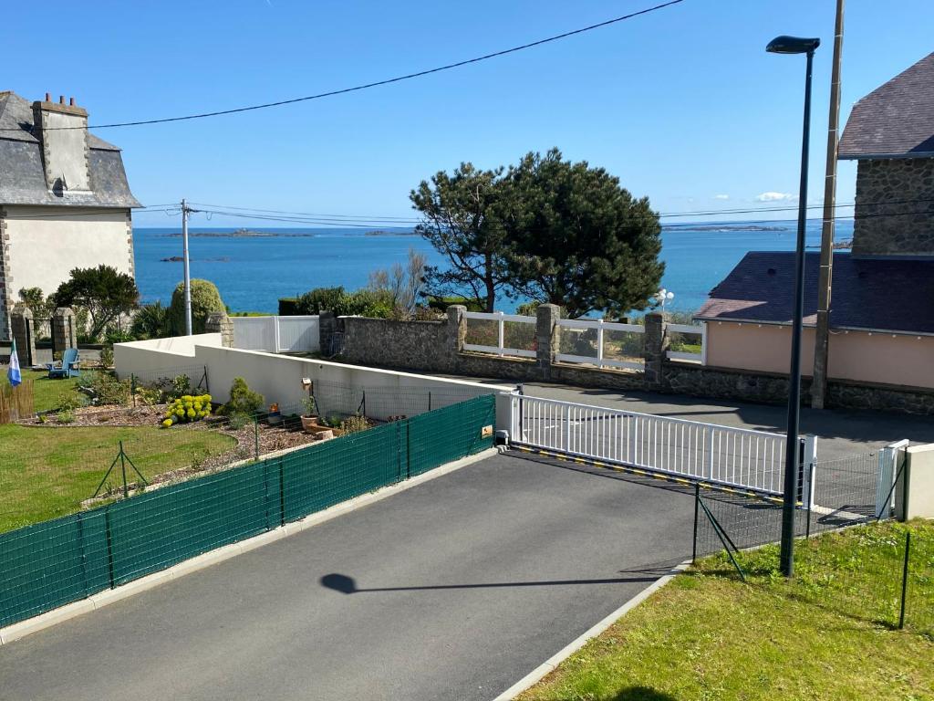 Eine Straße mit einem Zaun und dem Ozean im Hintergrund in der Unterkunft Les embruns in Saint-Quay-Portrieux