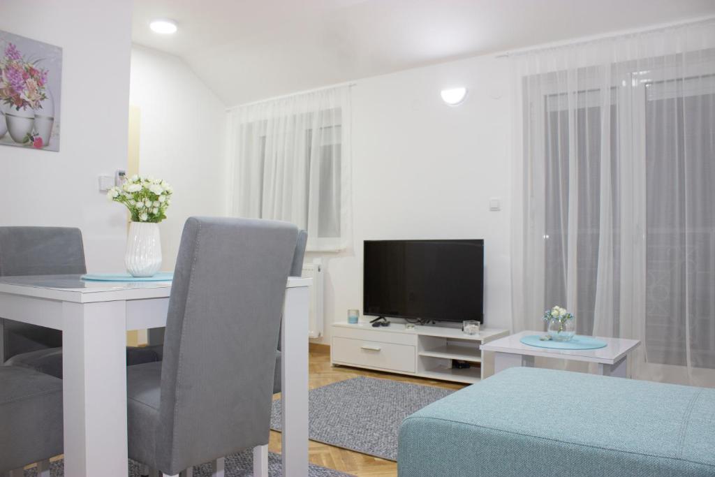 - un salon blanc avec une table et une télévision dans l'établissement Sweet Home Vrnjačka Banja, à Vrnjačka Banja