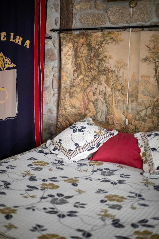 a bedroom with a bed with a painting on the wall at Casa da Vila in Sortelha