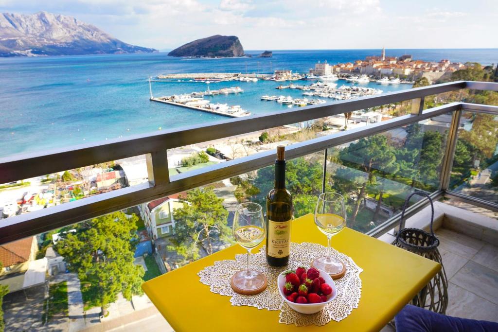 Four Views Apartments في بودفا: طاولة مع زجاجة من النبيذ وصحن من الفاكهة