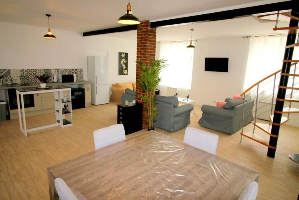 un salon avec une table à manger et un salon dans l'établissement Maison au bord du canal, à Moret-sur-Loing