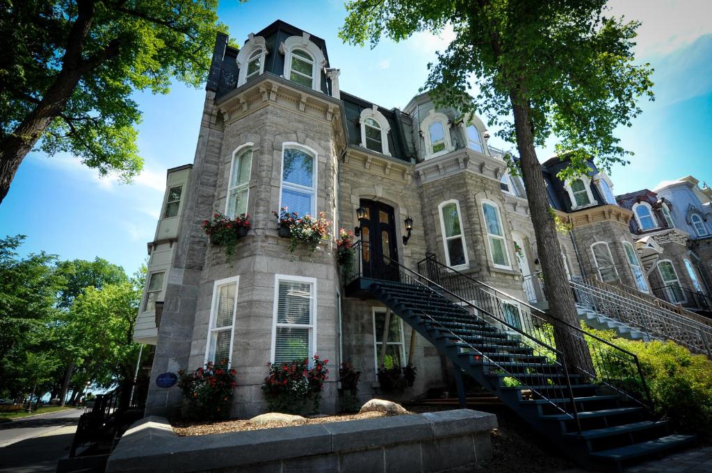 Un grand bâtiment en pierre avec des escaliers se trouve juste devant. dans l'établissement Le 555 Grande allée, à Québec