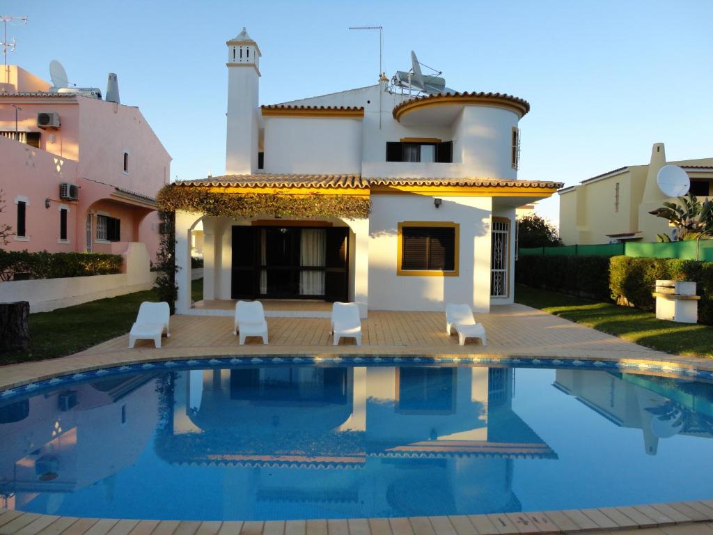 a villa with a swimming pool in front of a house at Villa Cavaco in Vilamoura
