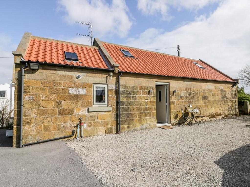 a small stone building with a red roof at Stable Cottage in Stoupe Brow