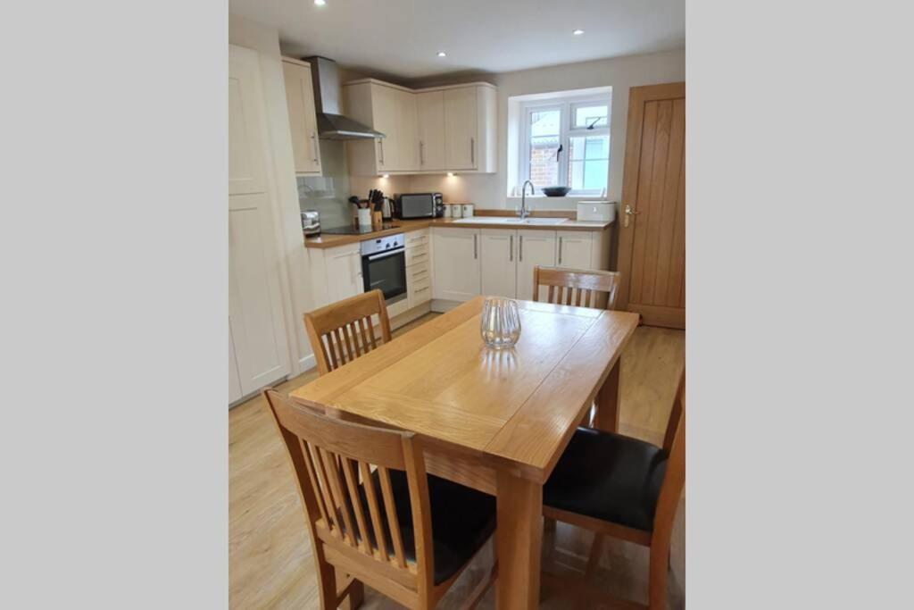 a kitchen with a wooden dining room table and chairs at Renovated cosy cottage within Cranborne Chase in Handley